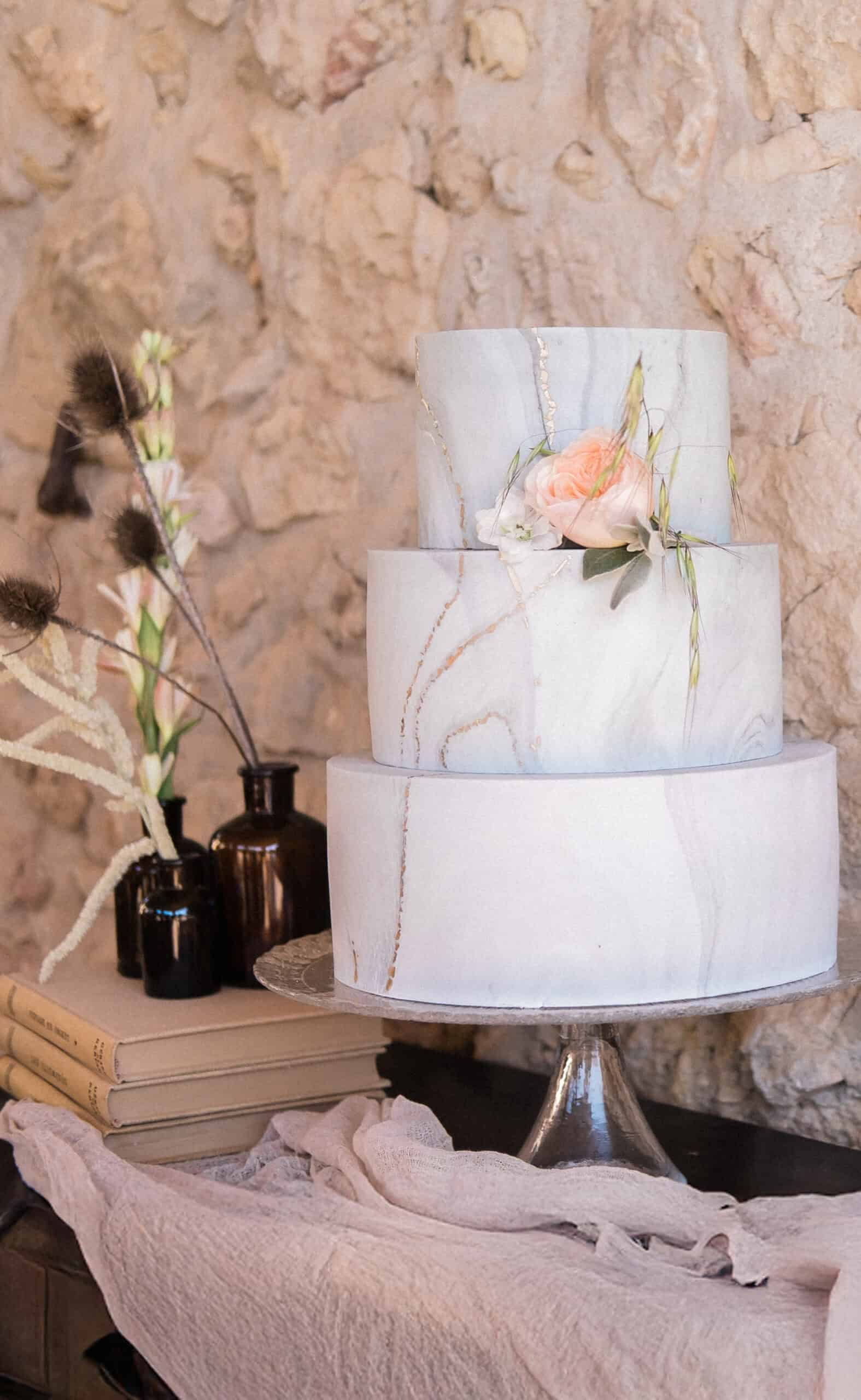 Elegant three-tier marble wedding cake with peach flower, rustic Provence venue