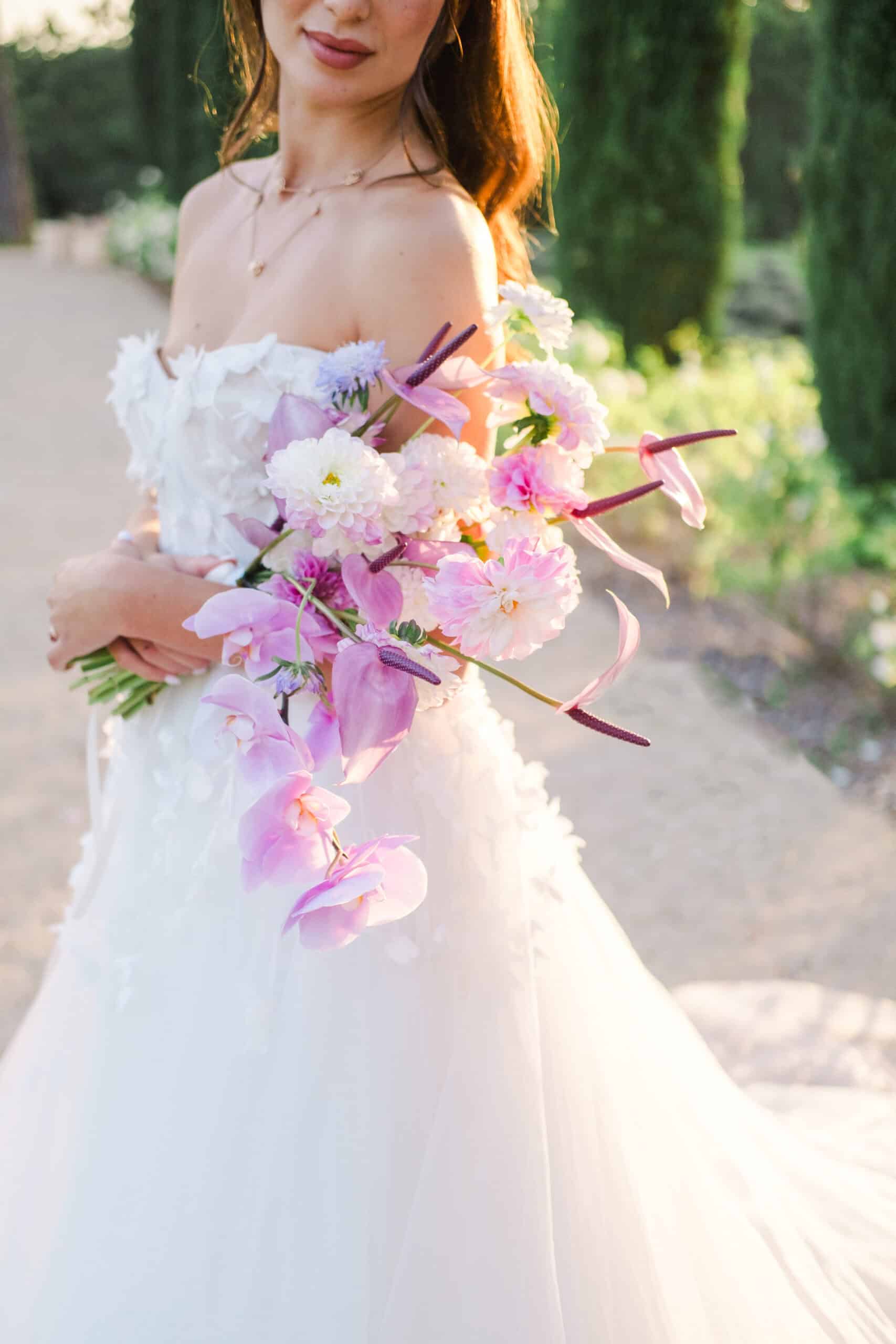 Portrait poétique de la mariée tenant un bouquet de fleurs fraîches pastel au coucher du soleil, en Provence.