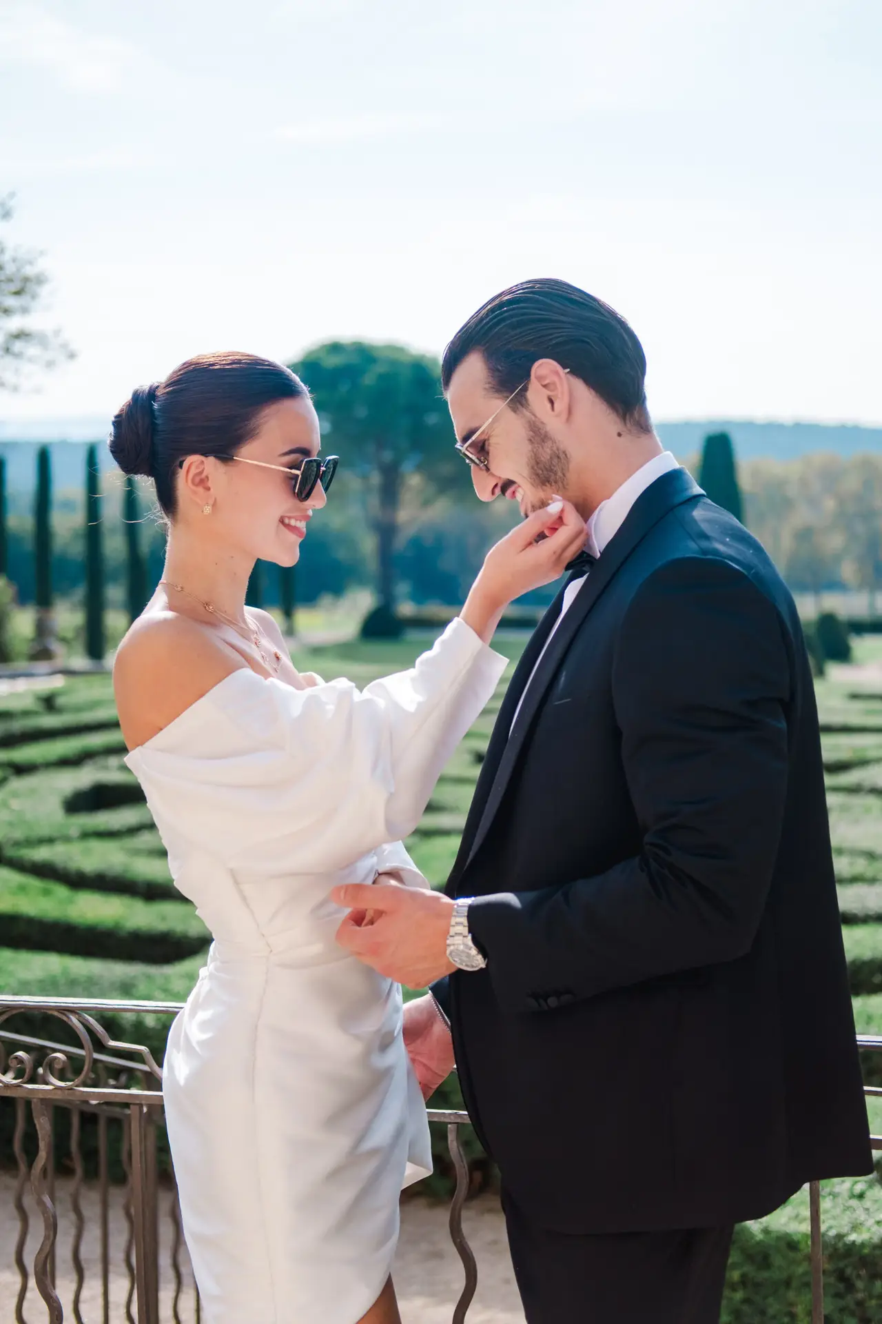 Couple in elegant black and white attire sharing a moment in sculpted gardens of Château de la Gaude — French sophistication.
