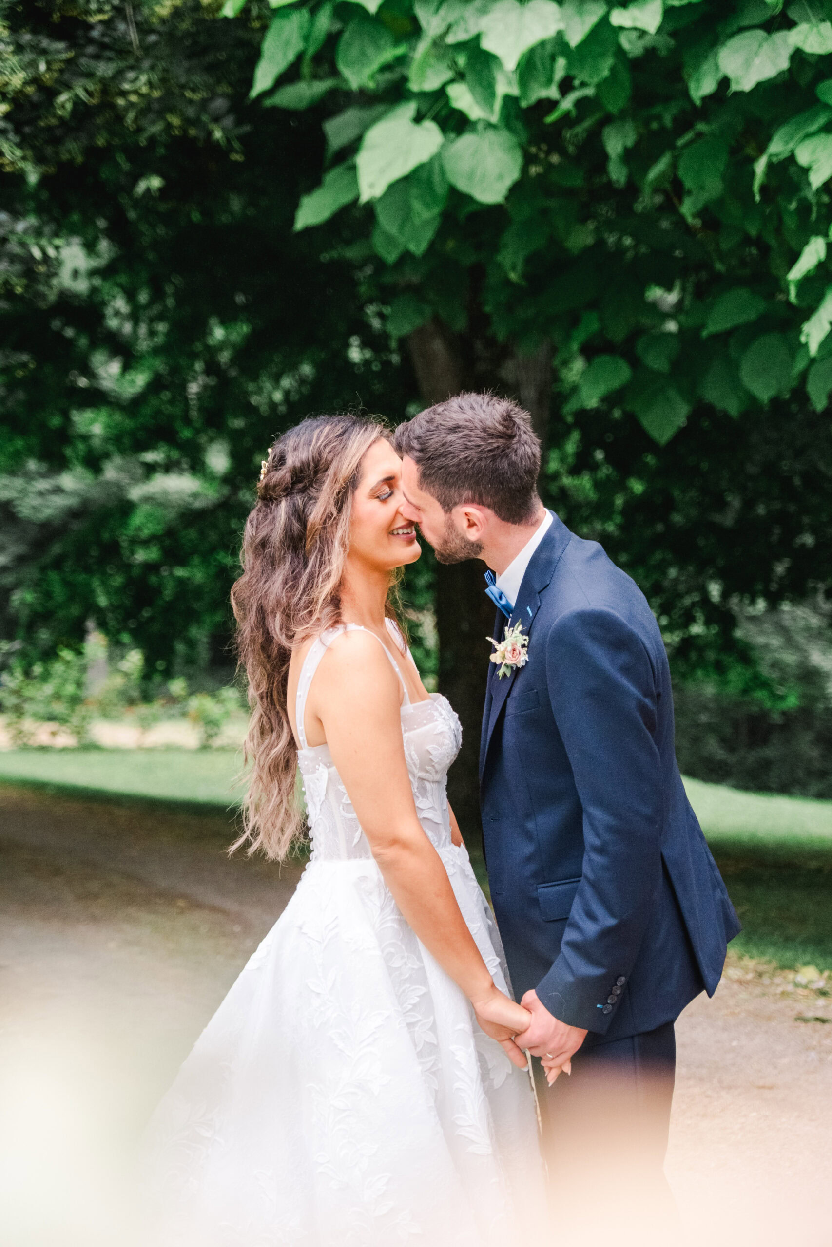 Intimate moment between bride and groom beneath tall trees at Château Fengari — raw emotion and soft light.