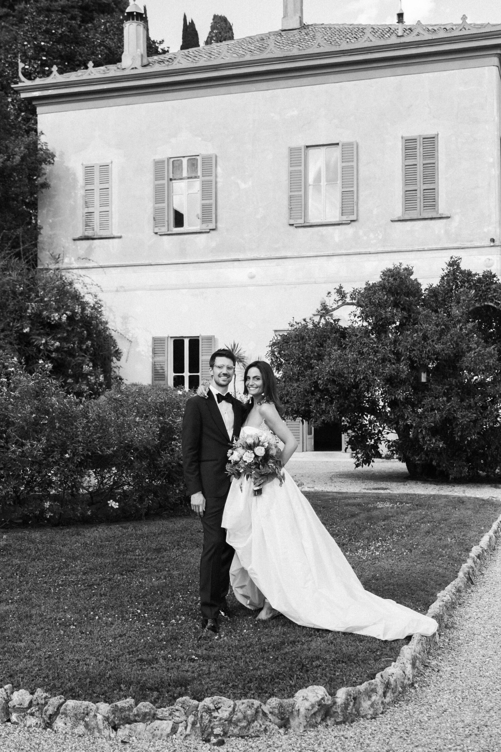 Bride and groom pose in front of Villa Pizzo during their destination wedding on Lake Como — refined and romantic.