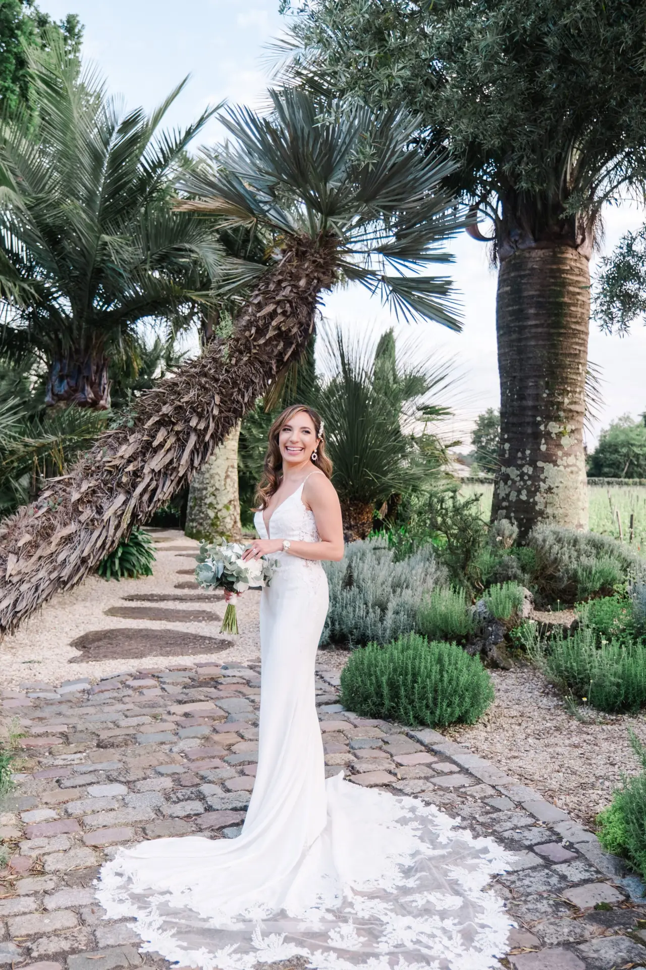Bride in a modern off-the-shoulder wedding dress walking in soft sunlight at Château Pape Clément
