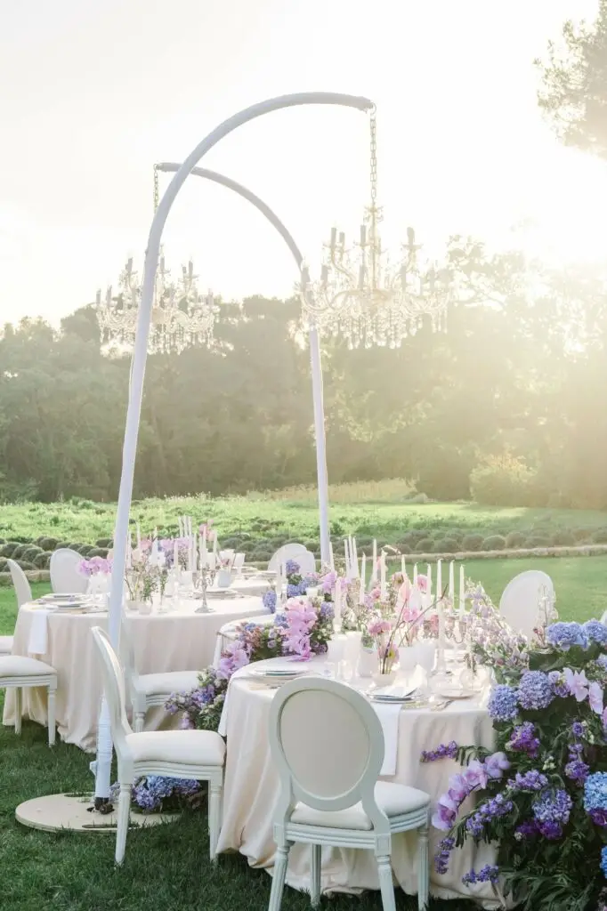 Outdoor wedding dinner tables with chandeliers and purple flowers at Château de la Gaude.