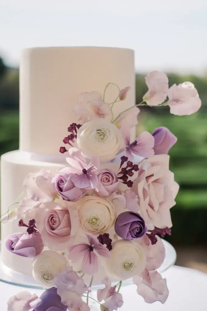 Elegant luxury wedding cake with purple floral decorations at Château de la Gaude in Provence, captured by Julien Boyer, French wedding photographer