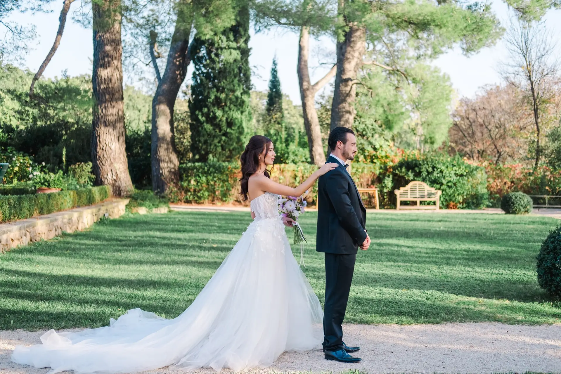 Bride approaching the groom from behind for a first look in the gardens of Château de la Gaude