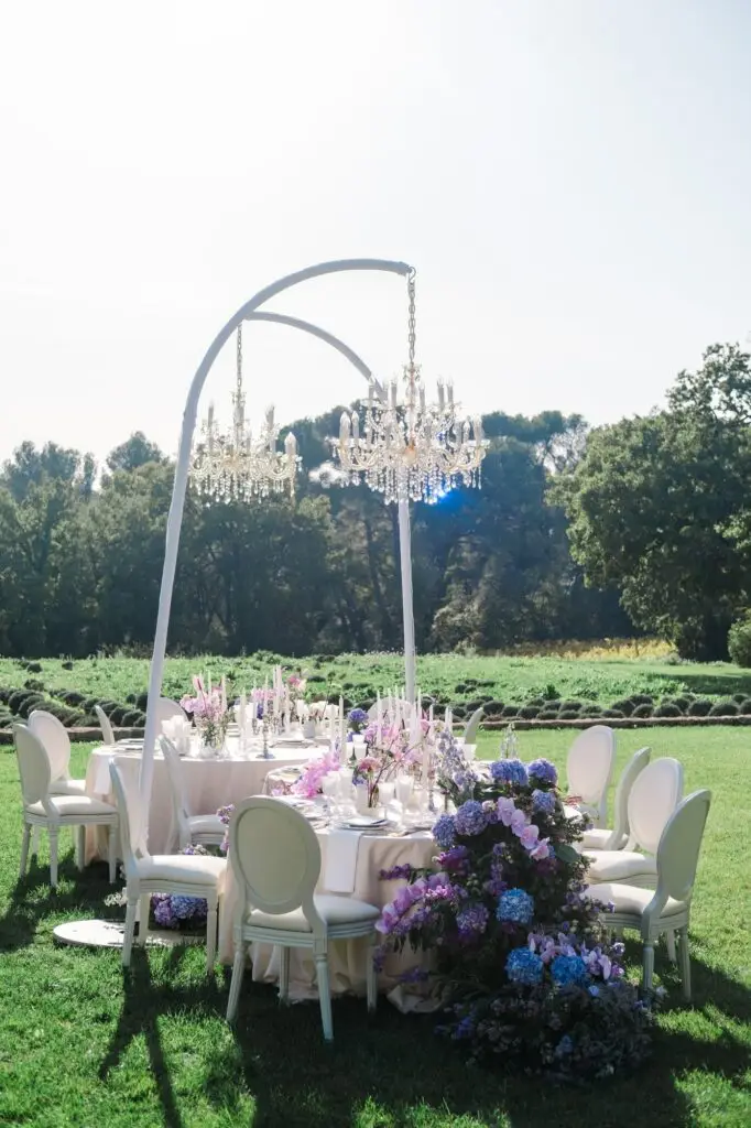 Luxury Provence wedding reception table decor with chandeliers and purple blooms at Château de la Gaude, photographed by Julien Boyer, French wedding photographer