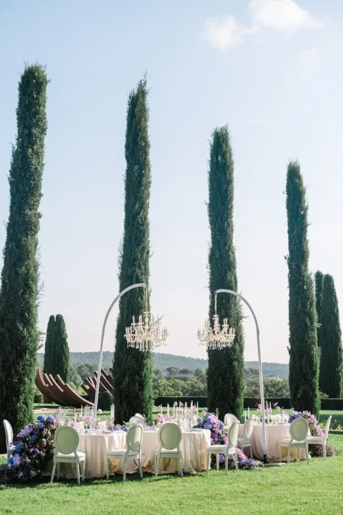 Among cypress guardians, chandeliers sparkle as love takes its seat—captured by Julien Boyer.