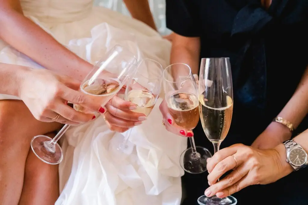 Close-up of the clinking glasses, golden bubbles rising. A symbol of joy, love, and the sparkling moments that define a wedding day, immortalized through the lens of Julien Boyer, French wedding photographer.