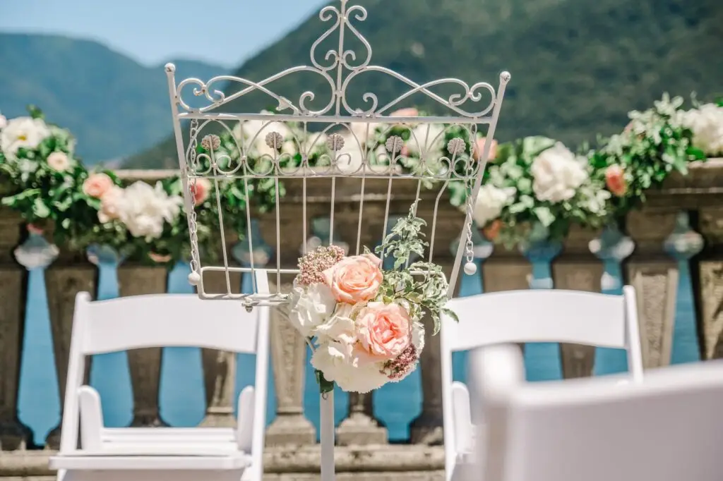 A delicate wedding detail: pastel flowers tied to an elegant stand, with Lake Como in the background.