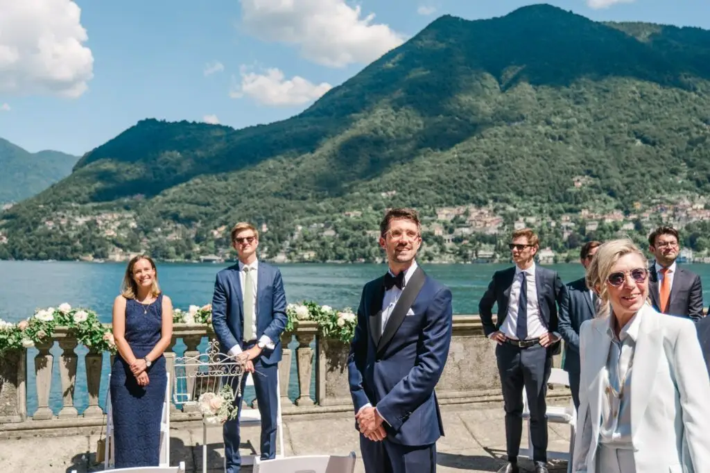 Guests in elegant suits and dresses gather at the waterfront altar, soaking in the sun and the scenery.