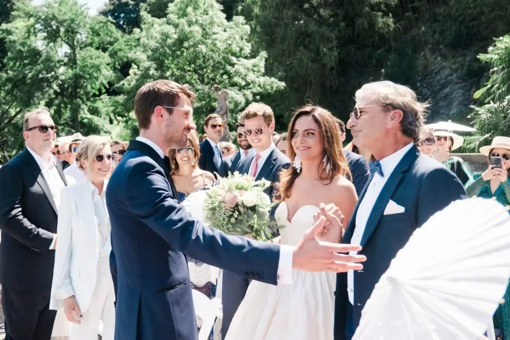 The groom warmly welcomes the bride, smiling as family and friends look on.