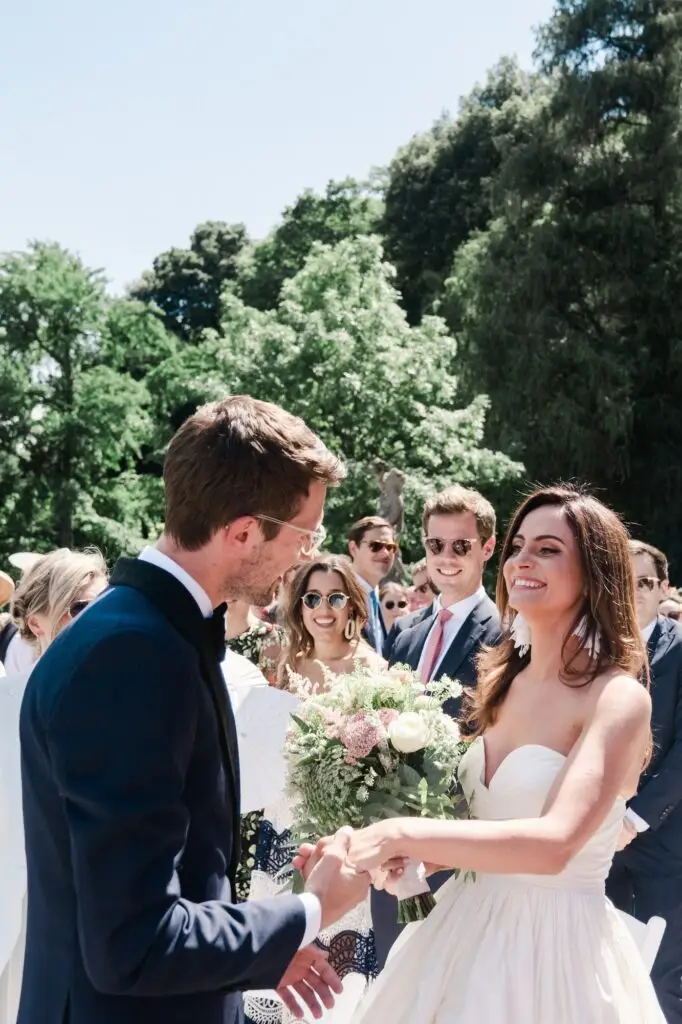 The bride and groom share a joyful moment as they hold hands, surrounded by cheering guests.