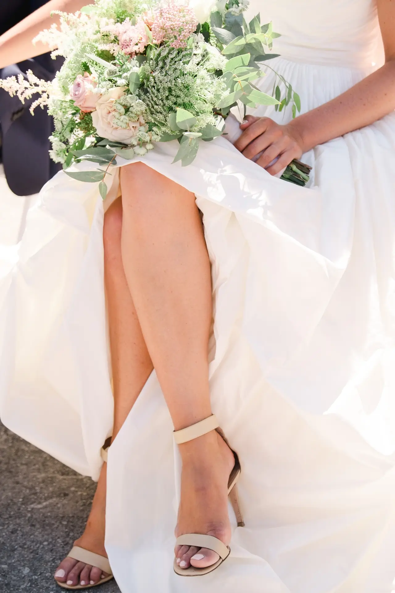 A romantic close-up of the bride’s bouquet and shoes, her dress gently flowing around her.