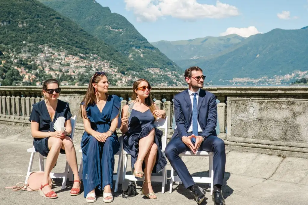 Wedding guests seated in elegant attire, enjoying the sunshine and the breathtaking views of Lake Como.