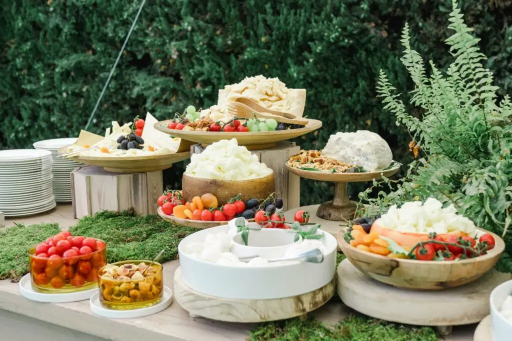Close-up of Italian wedding buffet with cheese, fresh grapes, cherry tomatoes, and rustic presentation.