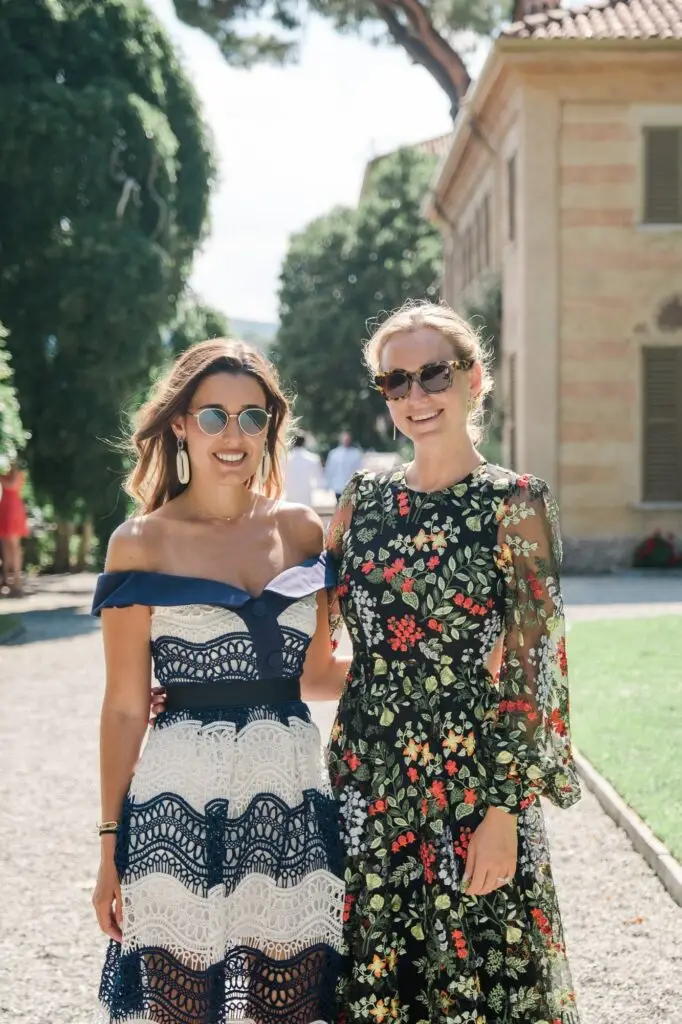Two stylish wedding guests posing in chic dresses in the gardens of Villa Pizzo, Lake Como.