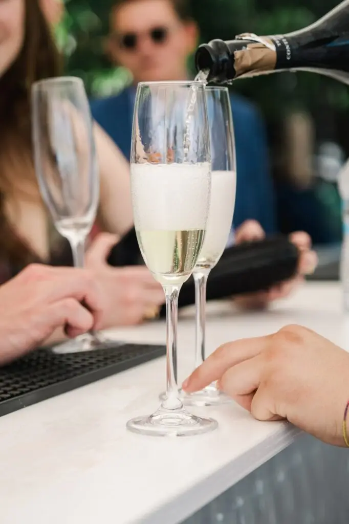 Champagne being poured into elegant flutes during cocktail hour, captured by Julien Boyer, French wedding photographer.