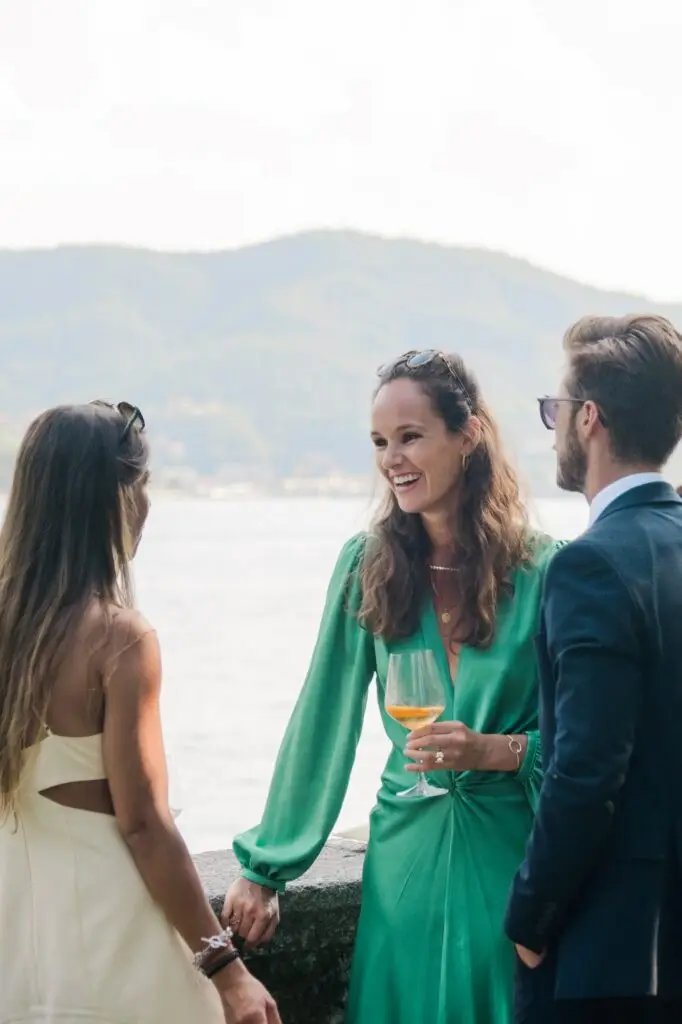 Guests laughing and enjoying drinks together at the waterfront terrace of Villa Pizzo in Lake Como.
