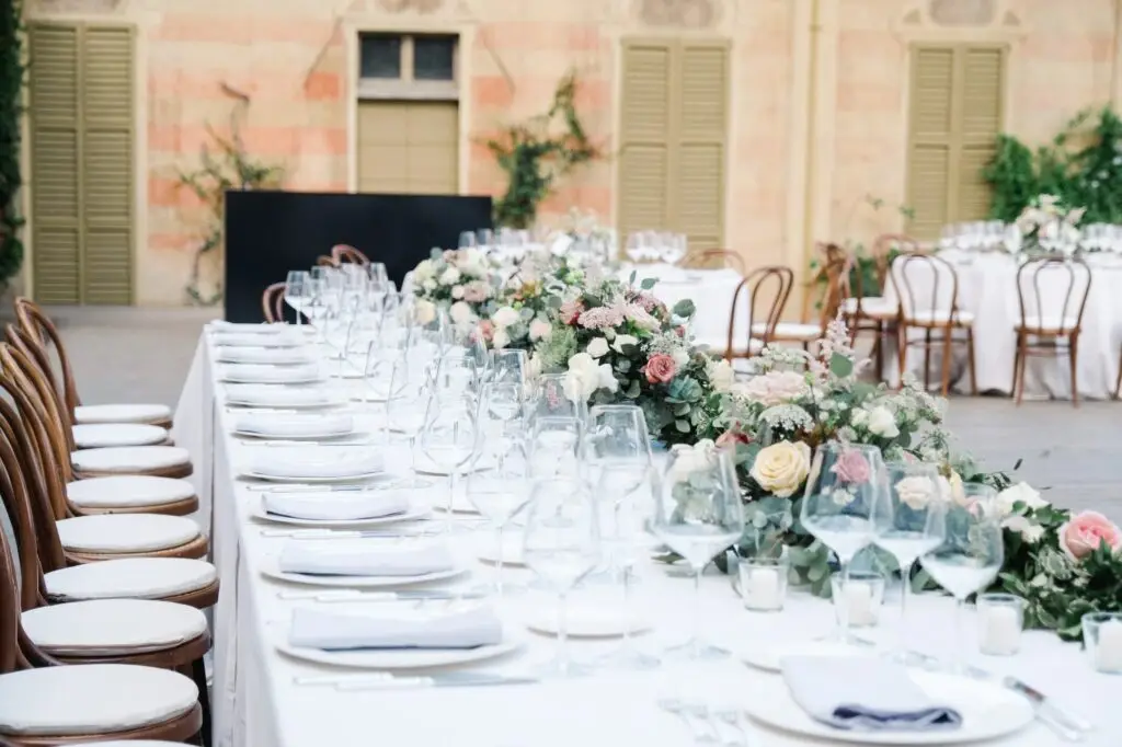 Elegant wedding reception table decorated with floral centerpieces, crystal glasses, and white linens.