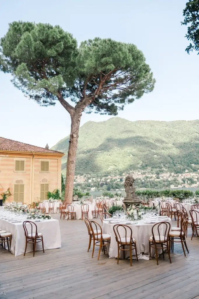 Elegant outdoor wedding reception setup at Villa Pizzo, Lake Como, with round tables and a panoramic mountain view.