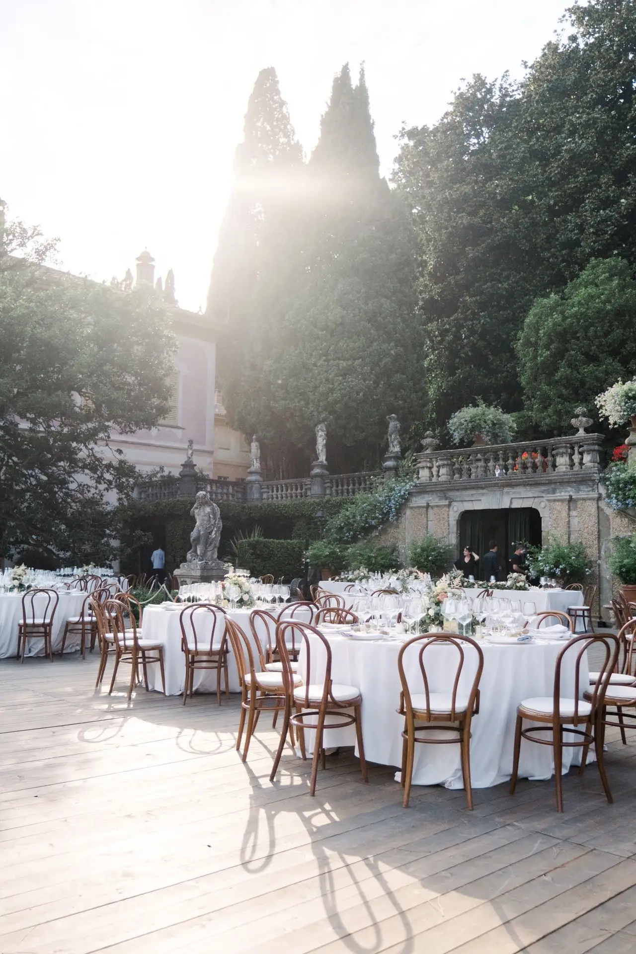 Sunlight streaming through the trees over the wedding dinner tables, creating a romantic atmosphere at Villa Pizzo.
