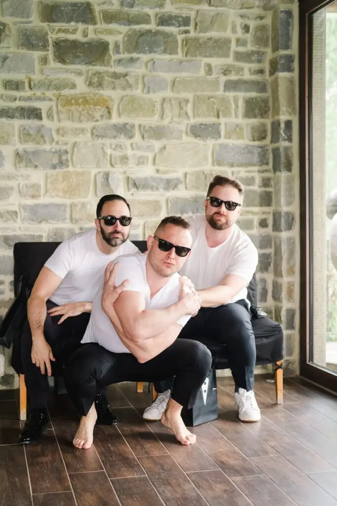 Groom and groomsmen in sunglasses posing playfully during wedding morning preparations at Borgo Corsignano, Tuscany