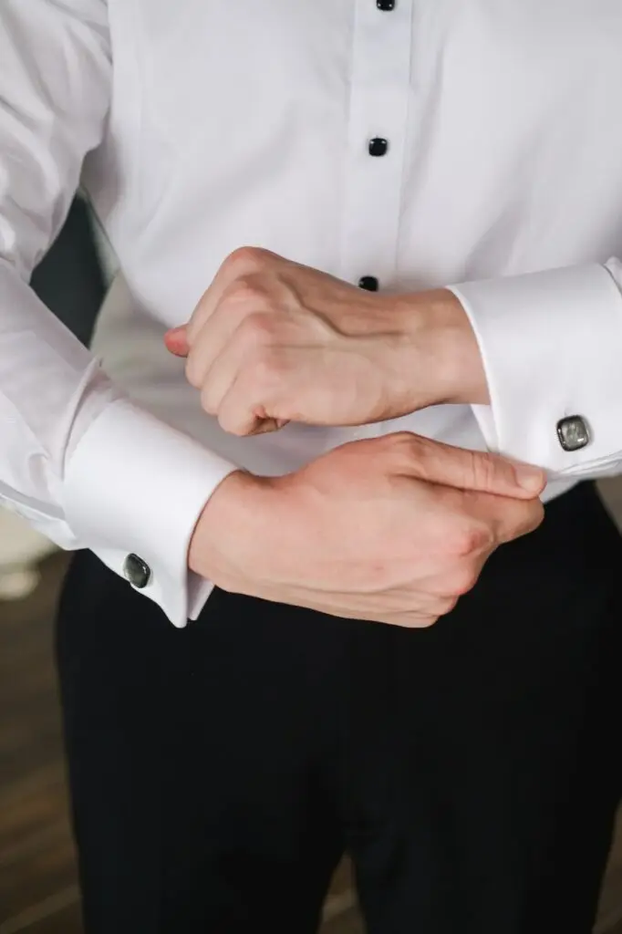 Close-up of groom adjusting elegant cufflinks during wedding preparations at Borgo Corsignano in Tuscany, Italy