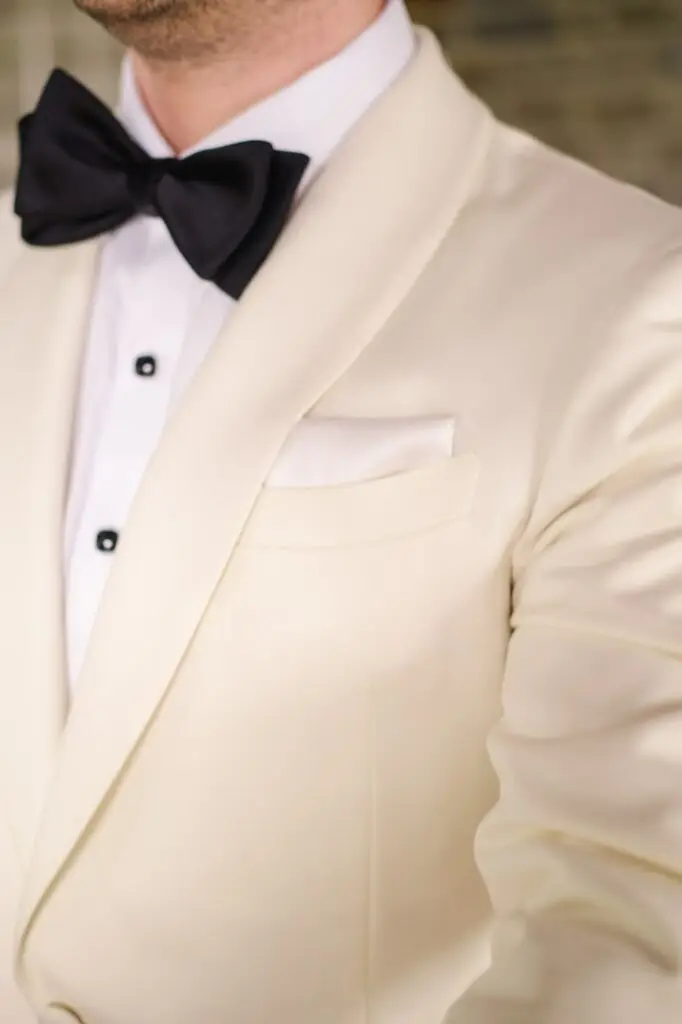 Close-up of groom’s white tuxedo and black bow tie – elegant wedding attire in Tuscany, Italy.