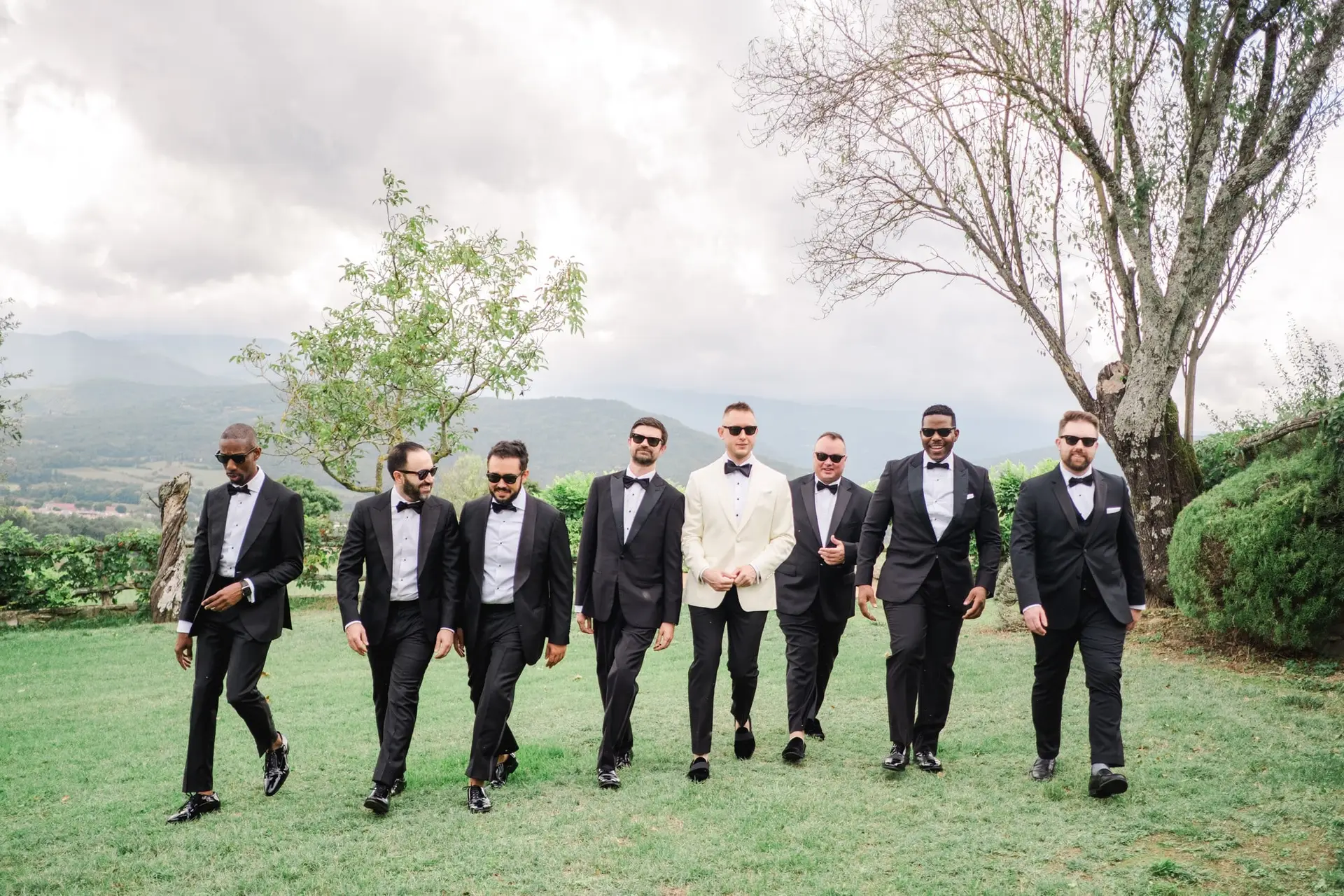 Groom and groomsmen walking in style in tuxedos at Borgo Corsignano wedding venue in Tuscany, Italy