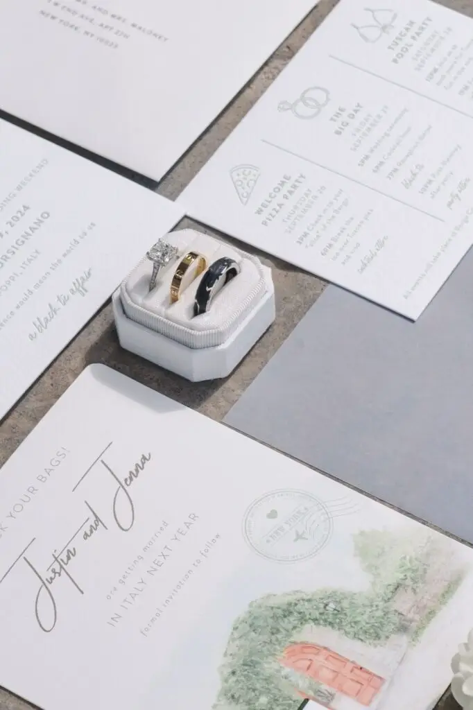 Close-up of wedding rings and engagement ring with elegant stationery suite for a destination wedding at Borgo Corsignano in Tuscany, Italy.