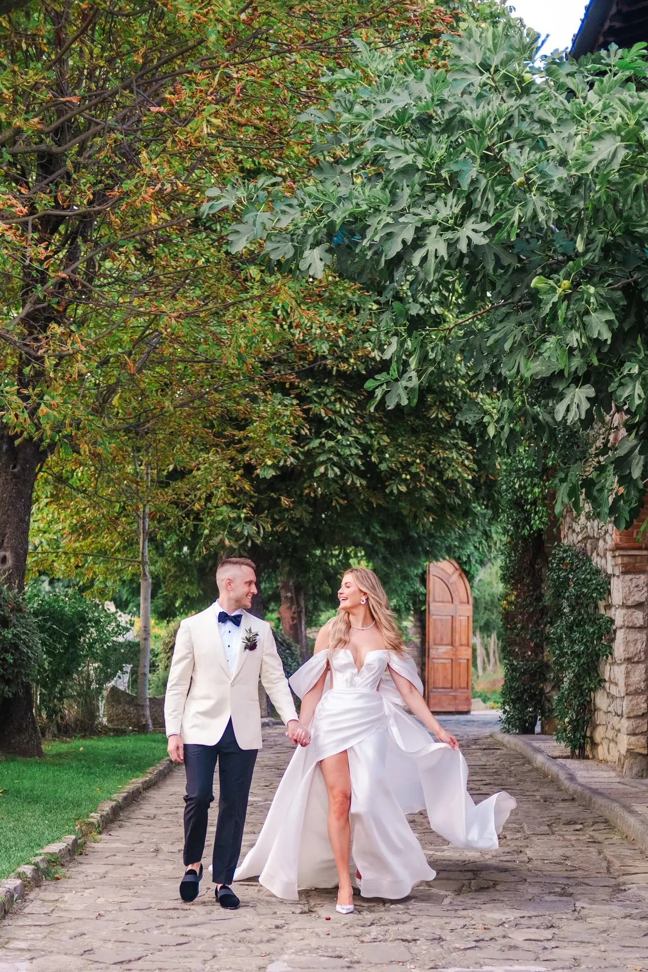 A romantic stroll under century-old trees, the couple glowing with happiness in the magical atmosphere of their wedding day.