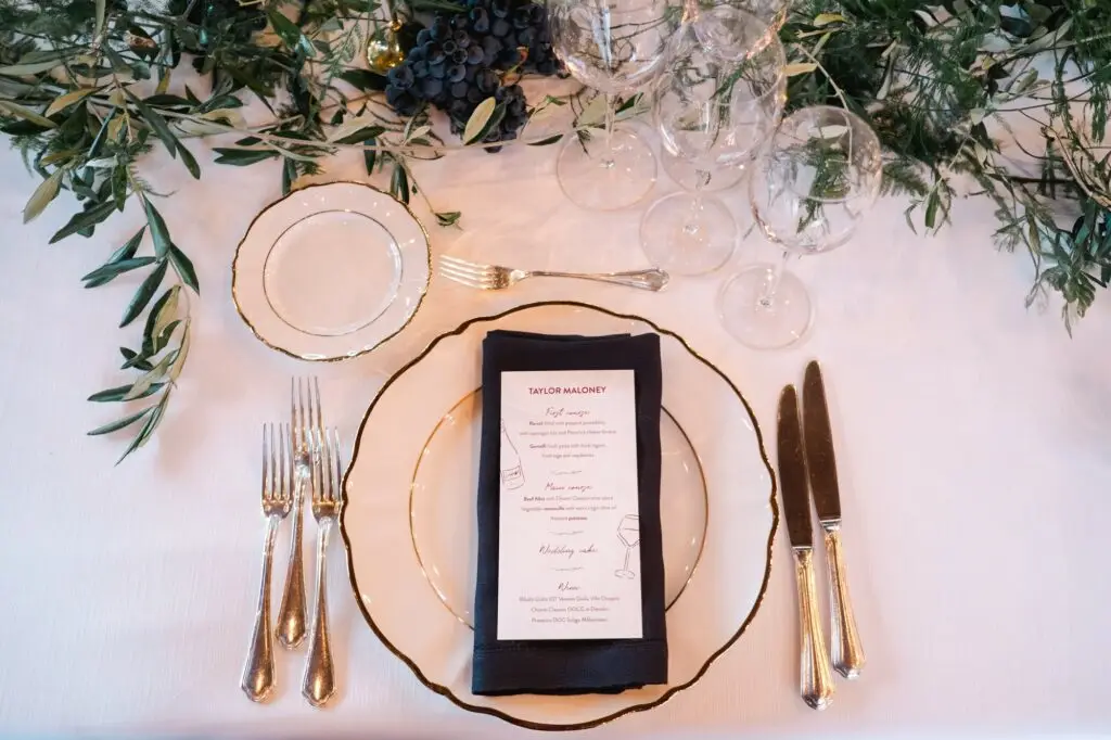 Elegant wedding table setting with neutral tones, golden cutlery, and a modern black and white menu card at Borgo di Corsignano.