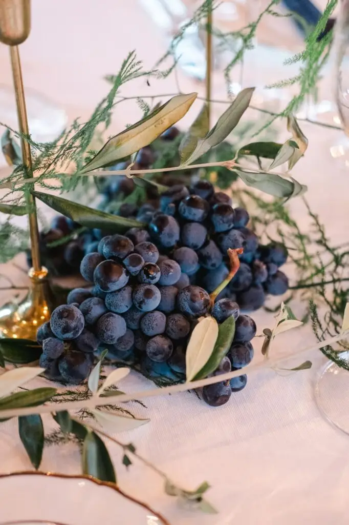 Fresh grapes and olive branches used as authentic Tuscan wedding decorations, symbolizing the region’s richness, captured by Julien Boyer.