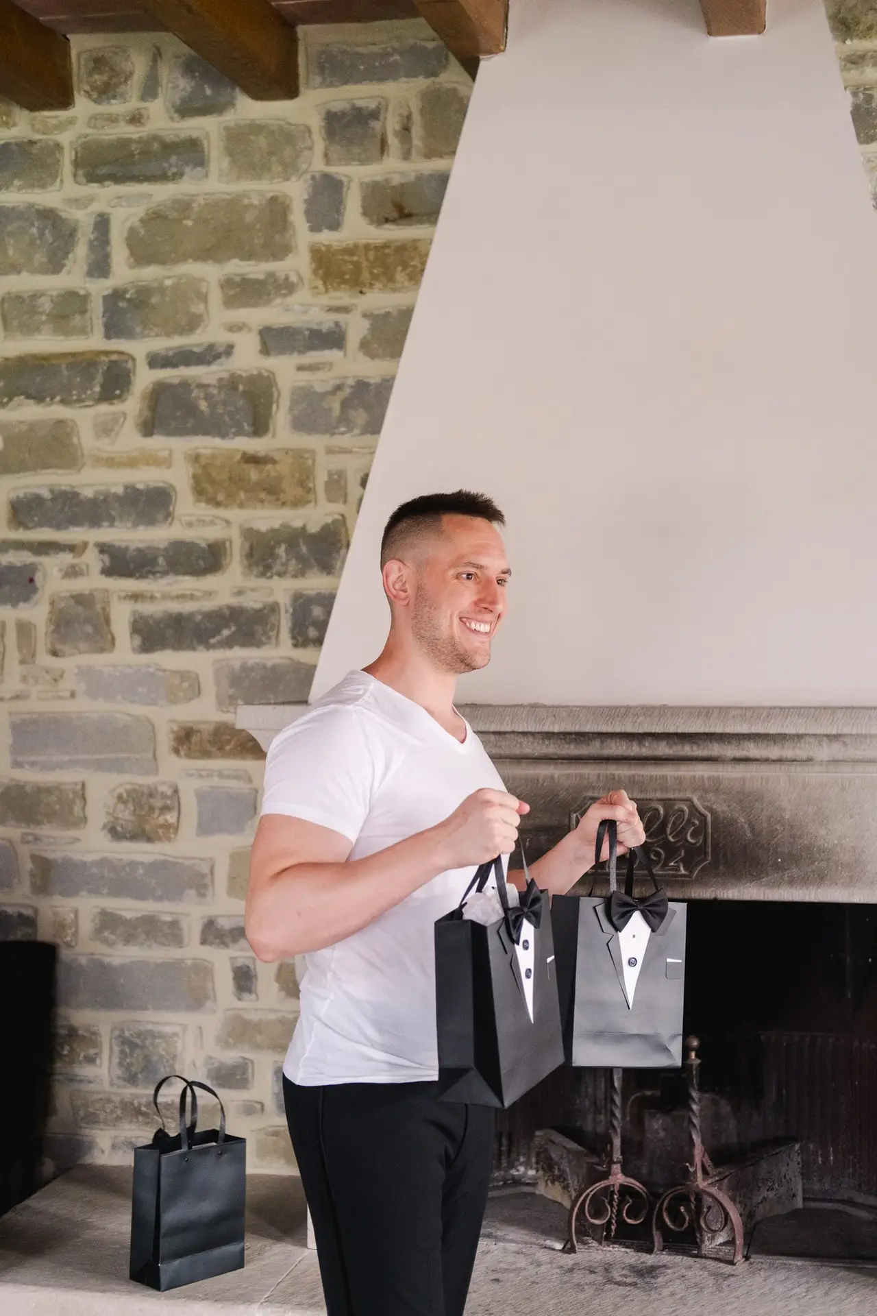 Groom holding groomsmen gift bags during wedding preparations at Borgo Corsignano in Tuscany, Italy