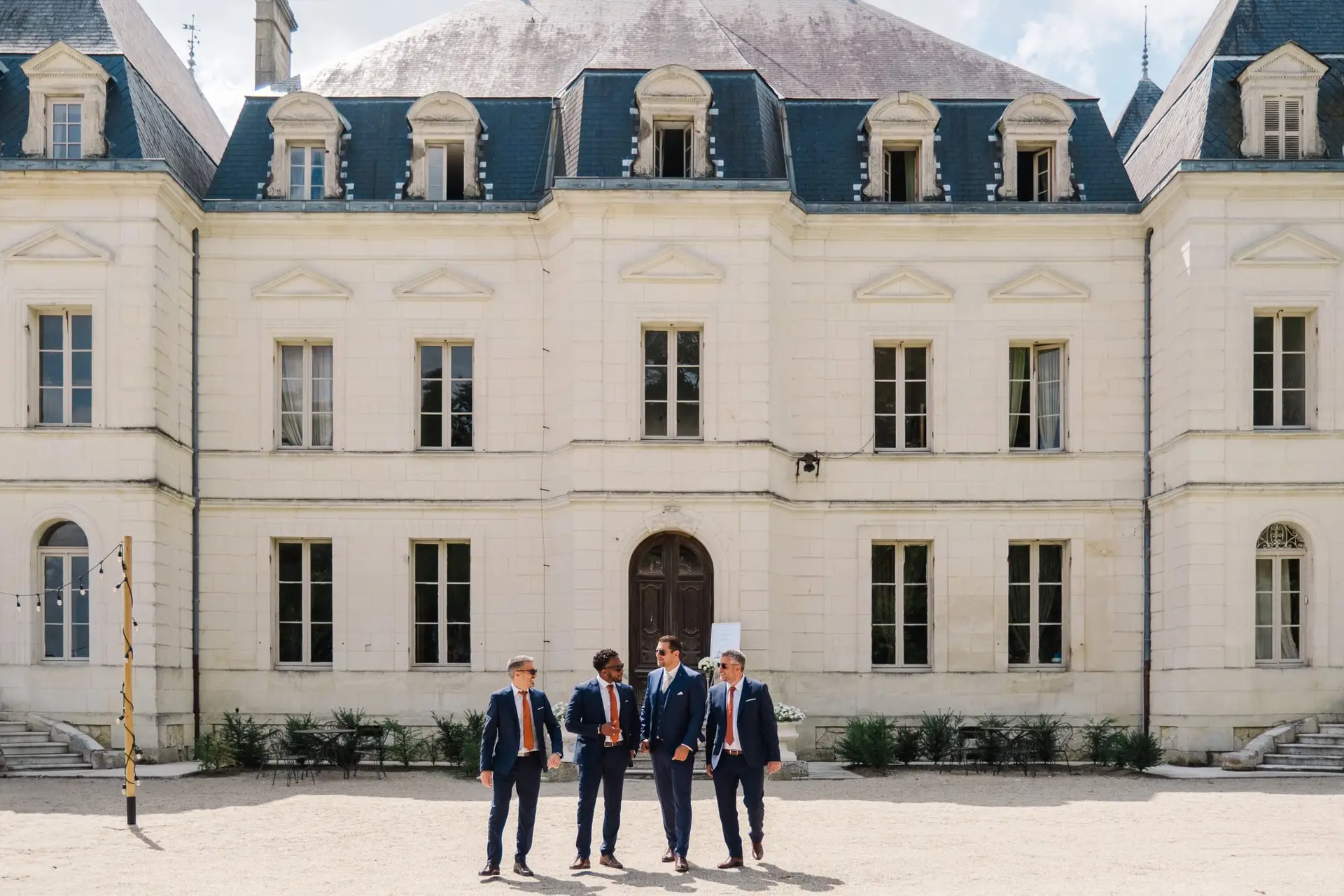 Invités du mariage marchant dans la cour du Château Fengari à Bordeaux, devant la façade classique du château.