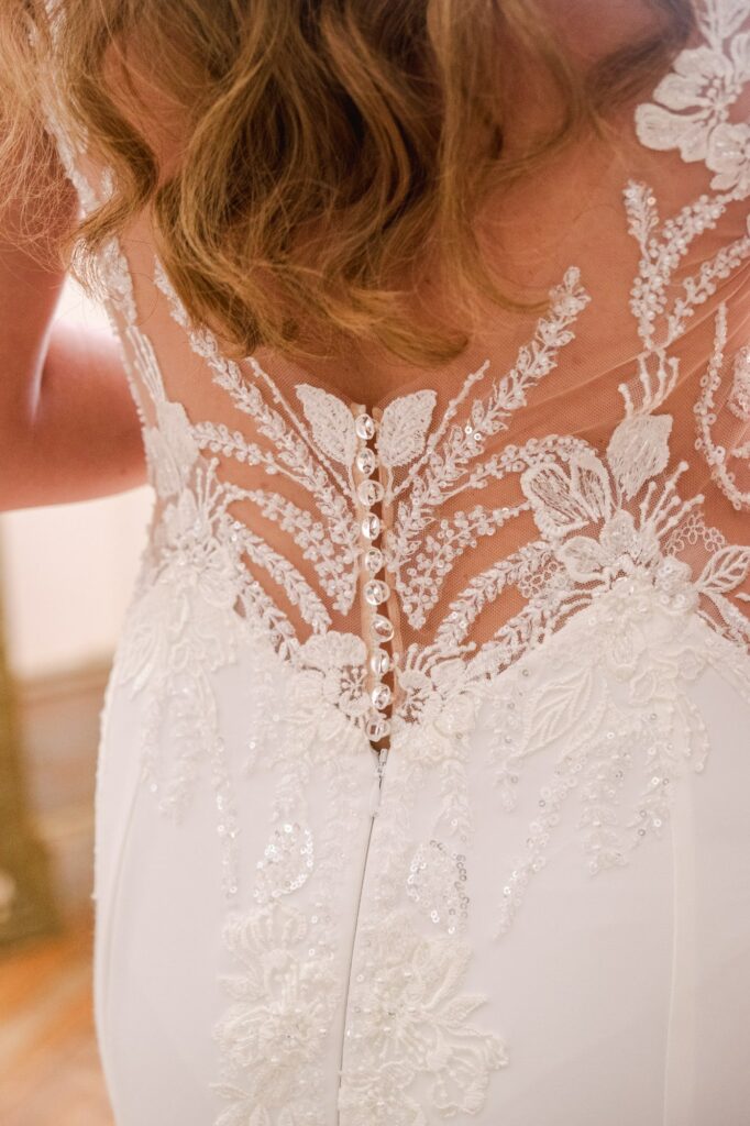 Gros plan sur le dos de la robe de mariée en dentelle, avec boutons recouverts et broderies florales.