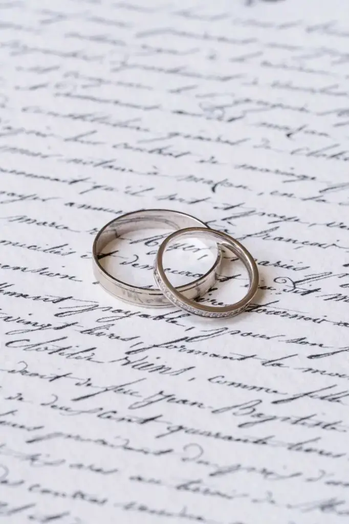 Les alliances, délicatement posées sur une lettre manuscrite, symbolisent l’union à venir.