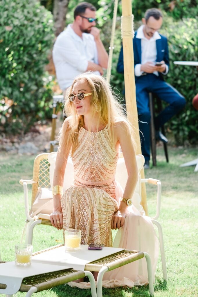 Une invitée élégante est assise dans le jardin pendant le cocktail de mariage.