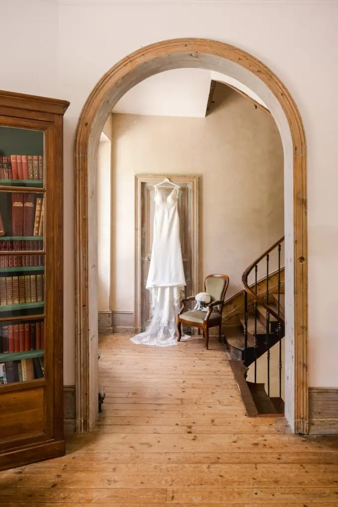 La robe de mariée se dévoile au cœur de l’architecture du château, encadrée par une arche ancienne et la douceur de la lumière.