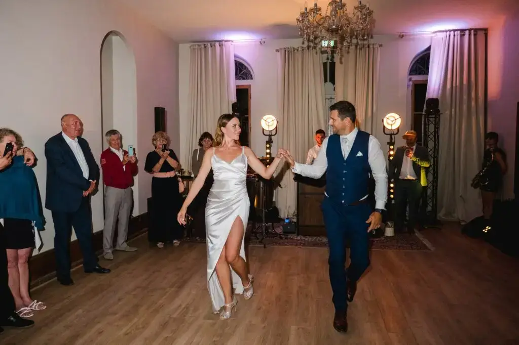 Entrée des mariés sur la piste de danse pendant la soirée de mariage au Château Fengari, près de Bordeaux, les invités entourent le couple sous les lumières chaleureuses de la salle, moment festif photographié par un photographe de mariage.
