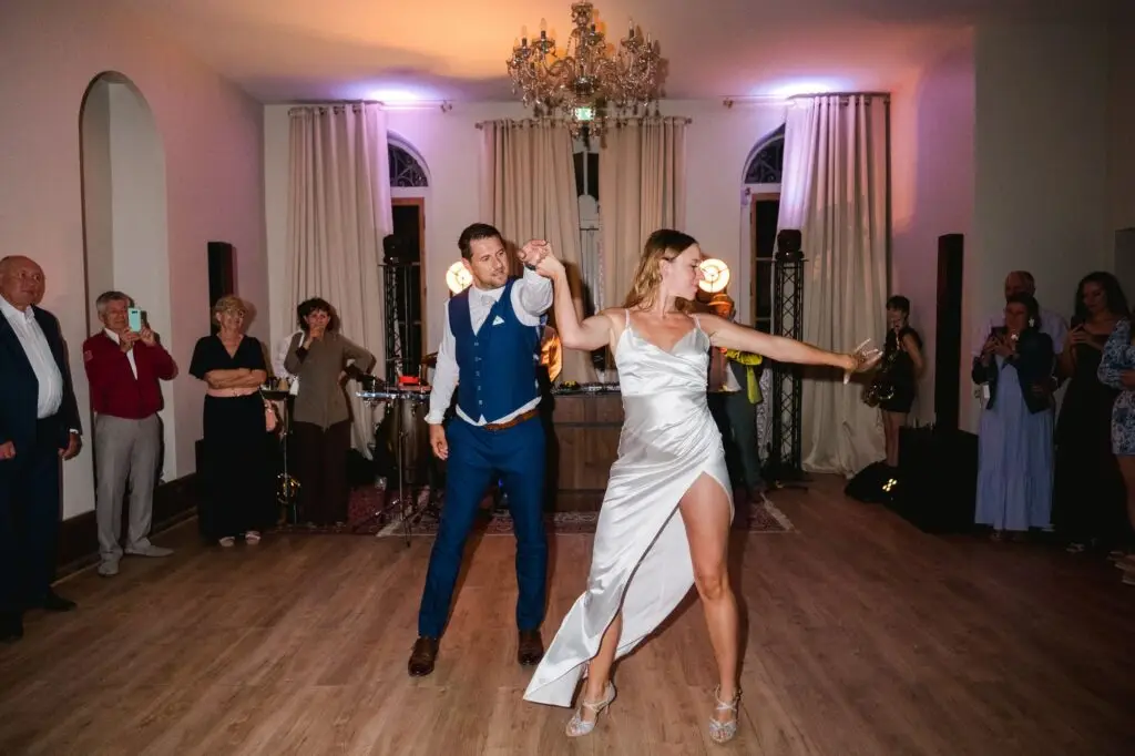 Capture d’un moment de danse en mariage avec un couple dans une salle chic, ambiance chaleureuse et lumière tamisée.