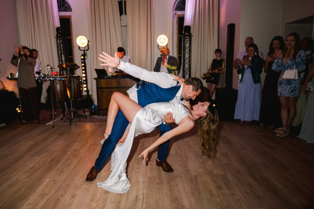 Un couple de mariés danse lors d'une soirée de mariage à Bordeaux, entouré d'invités, avec musique live en arrière-plan.