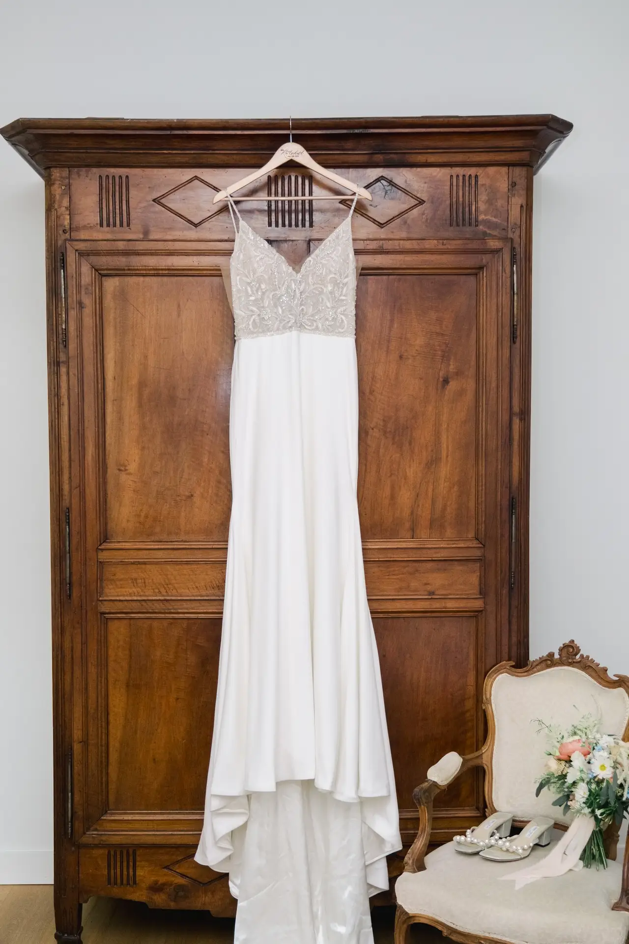 Robe de mariée suspendue dans une chambre du Château Gassies à Bordeaux, lumière naturelle et décor authentique.