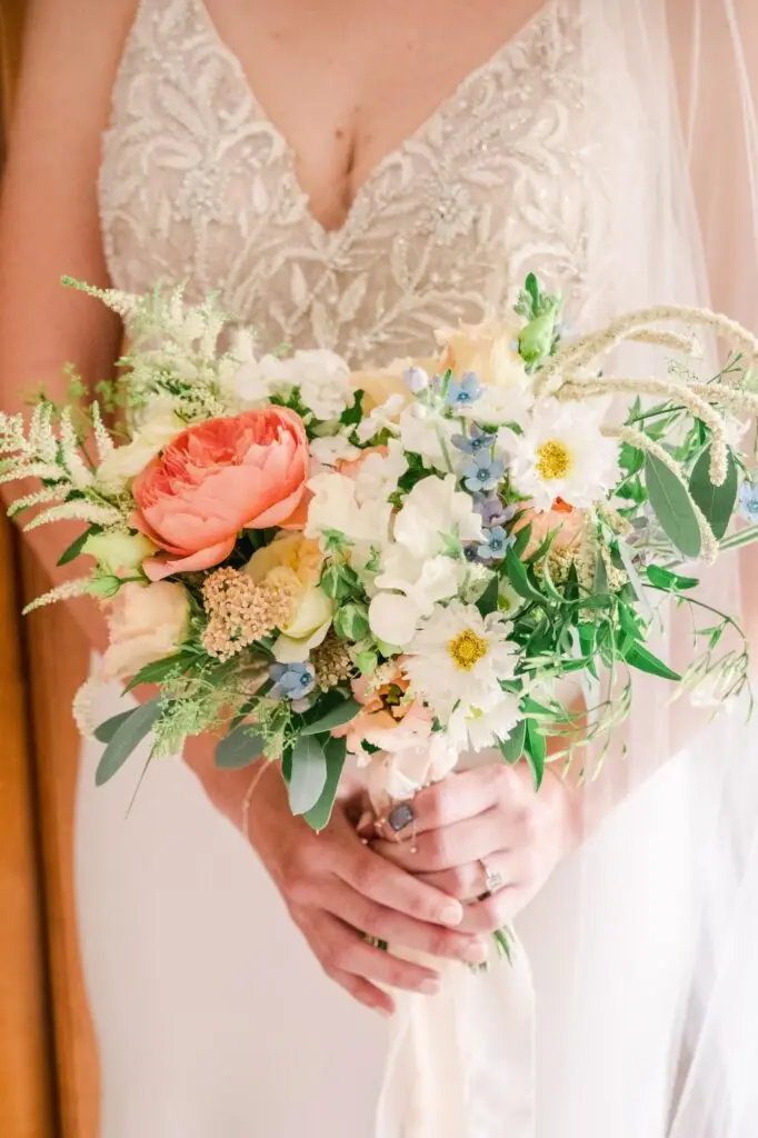 Détail du bouquet de la mariée aux fleurs pastel tenu devant la robe, photographié lors d’un mariage au Château Gassies à Bordeaux.