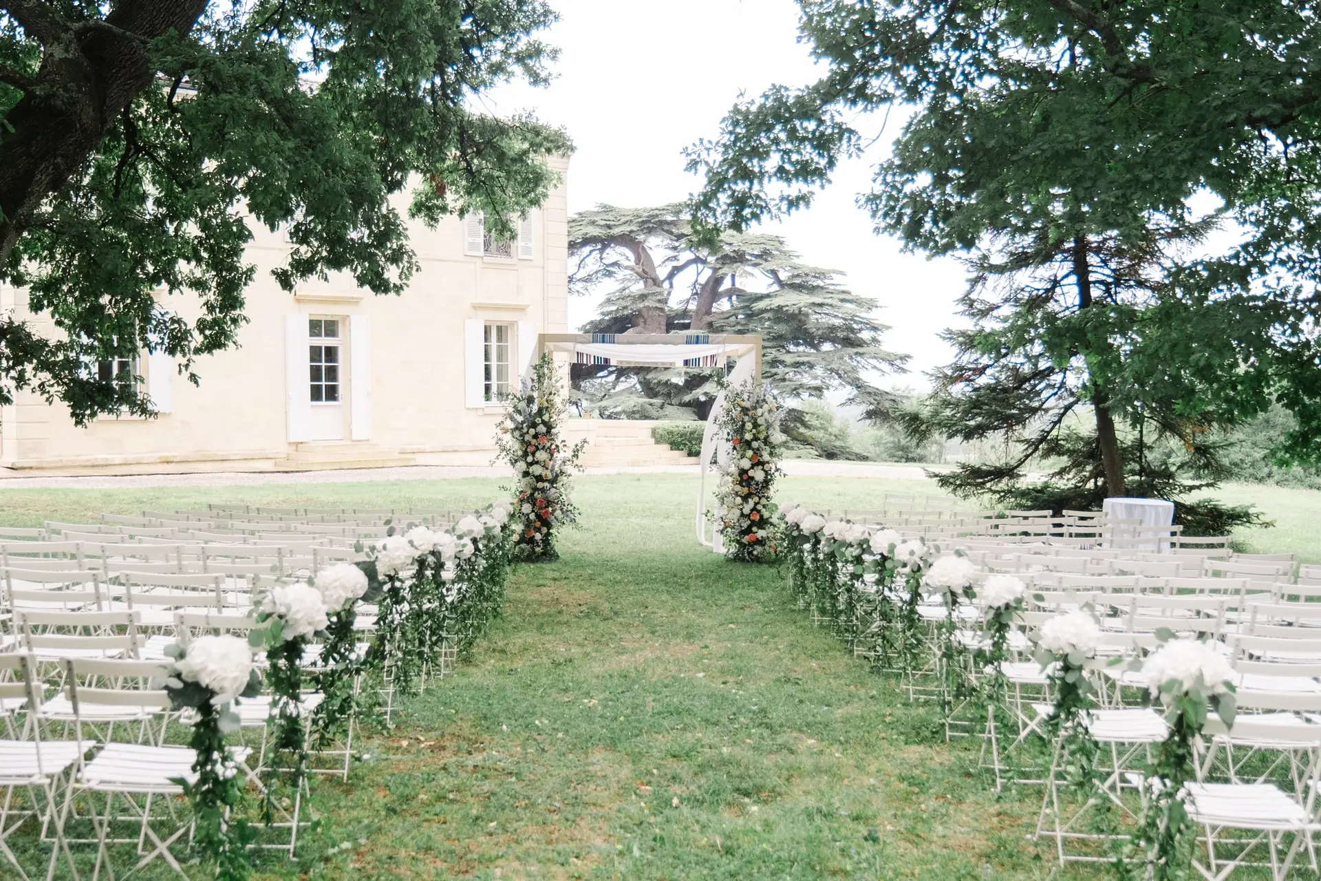 Cérémonie de mariage en plein air au Château Gassies à Bordeaux avec arche fleurie et allée décorée.