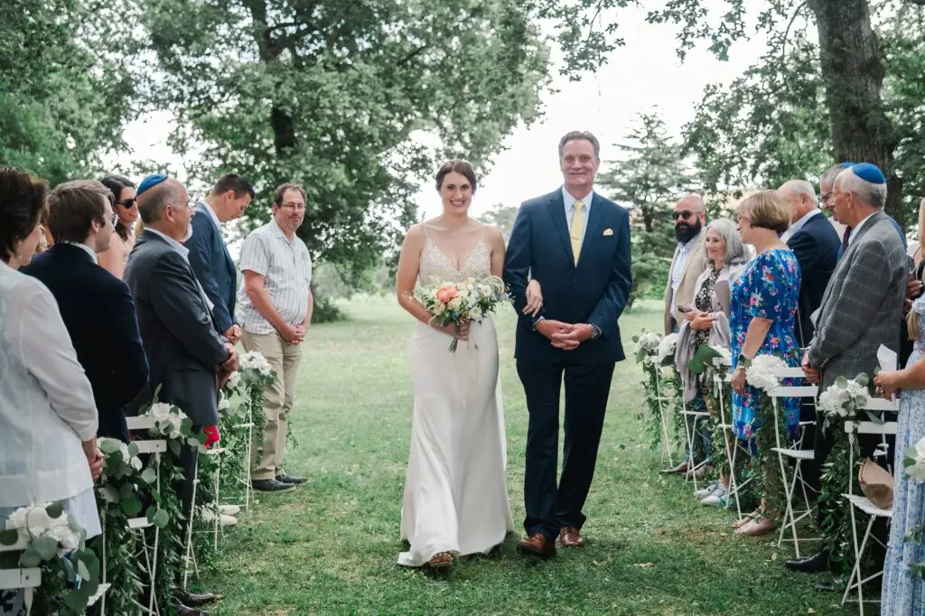 Mariée avançant dans l’allée au bras de son père lors de la cérémonie au Château Gassies à Bordeaux.