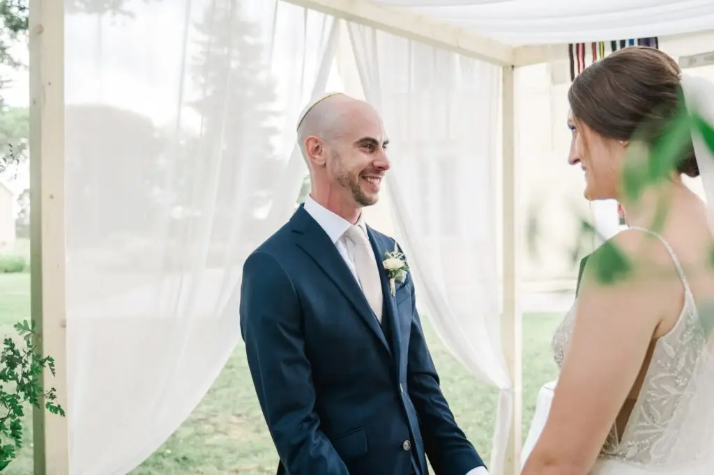 Marié souriant face à la mariée pendant la cérémonie de mariage en extérieur au Château Gassies à Bordeaux.