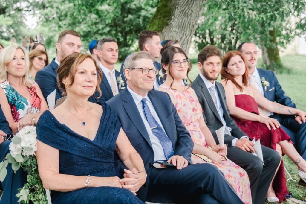 Parents des mariés assis au premier rang pendant la cérémonie de mariage en extérieur au Château Gassies à Bordeaux.