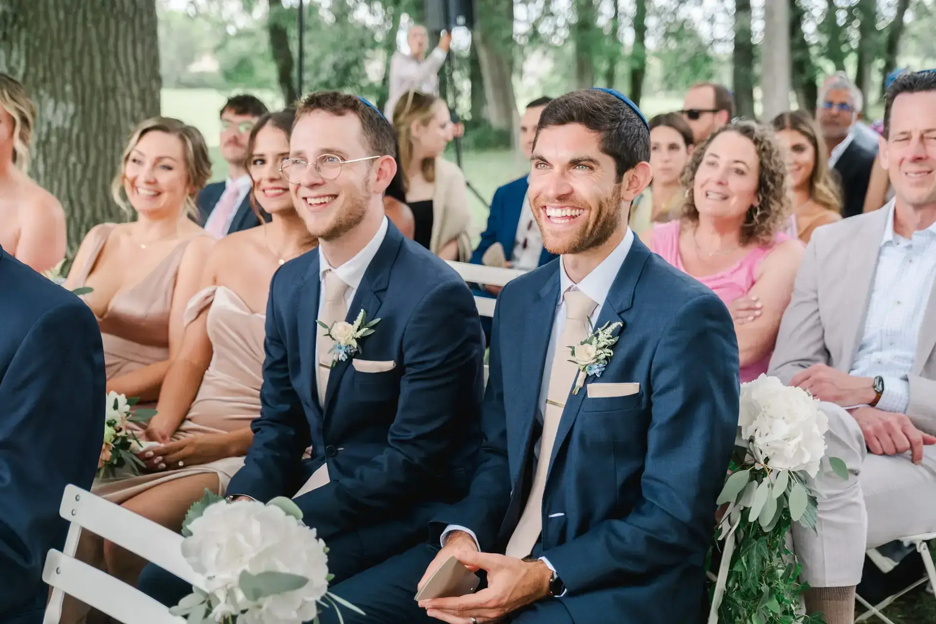 Invités souriant et émus pendant la cérémonie de mariage en extérieur au Château Gassies à Bordeaux.