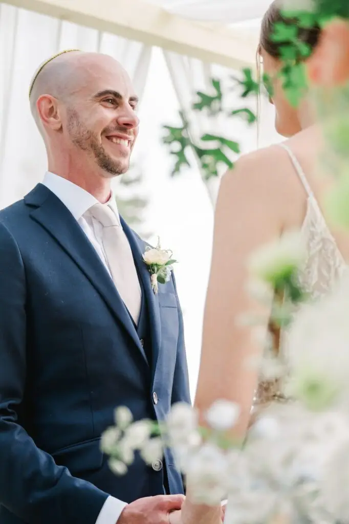 Marié souriant et regardant la mariée pendant l’échange des vœux au Château Gassies à Bordeaux.